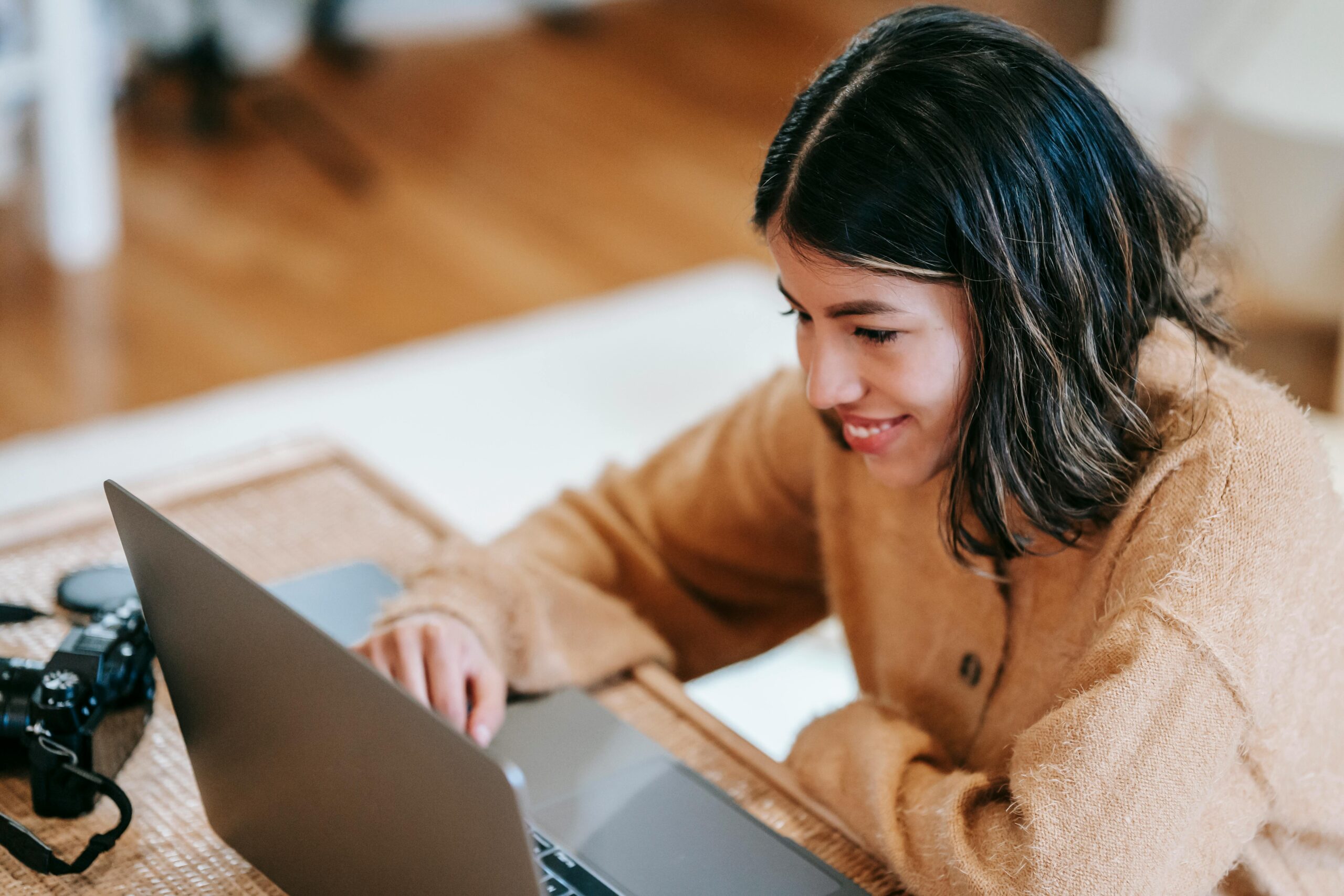 Young woman sitting at table working on laptop and smiling
